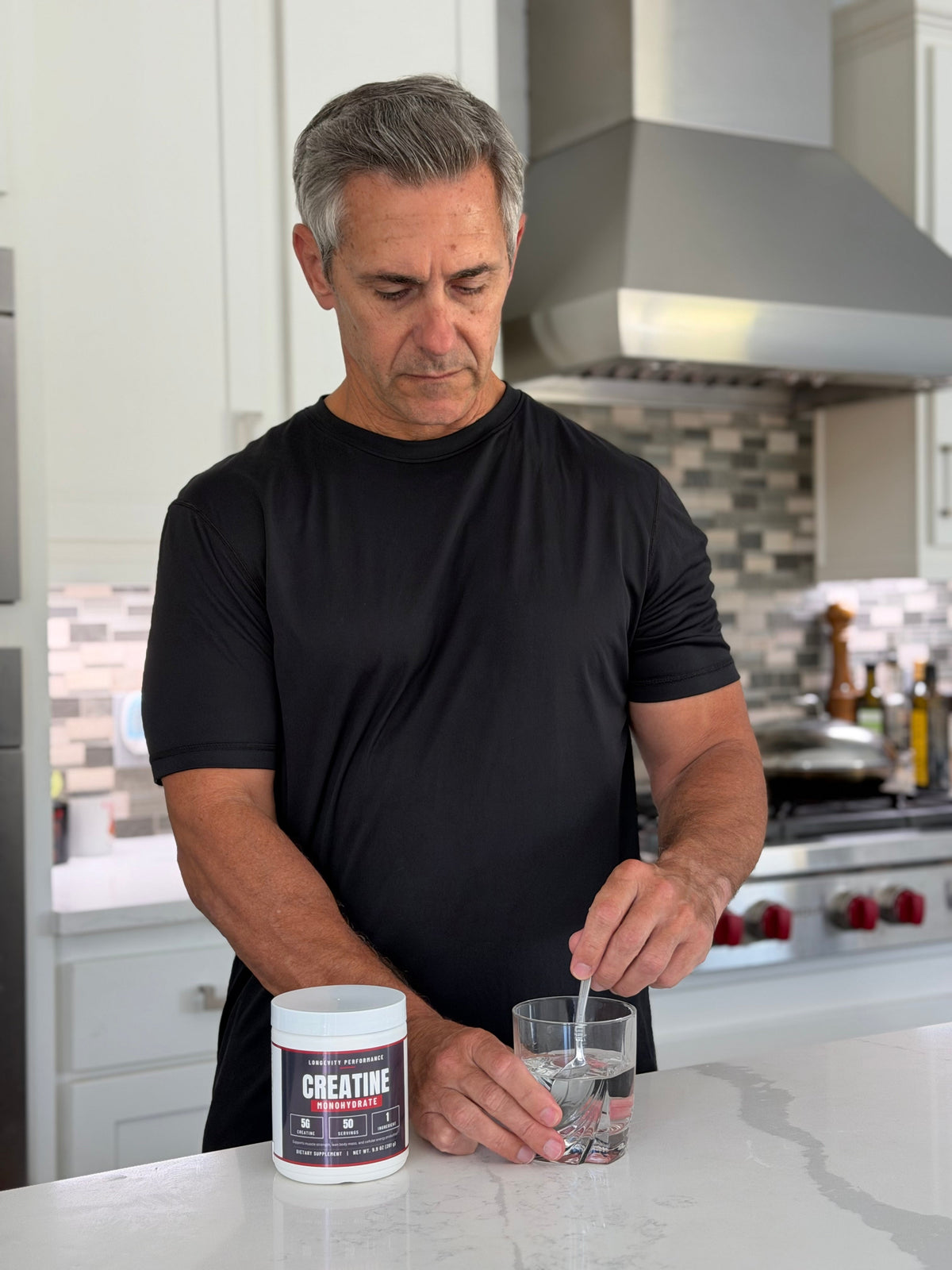 Luis Acevedo, founder of Longevity Performance, stirring Creatine Monohydrate into a glass of water in his kitchen