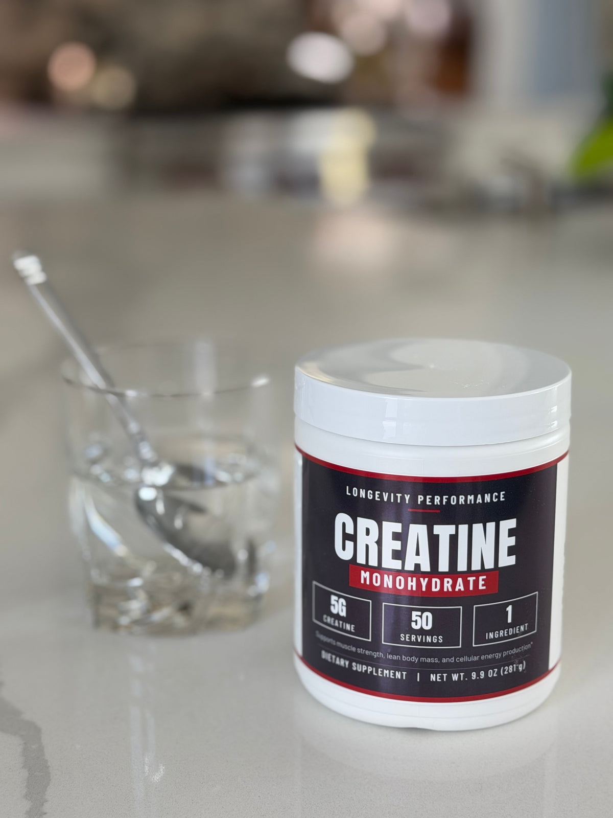 Longevity Performance Creatine Monohydrate jar next to a glass of water with a spoon