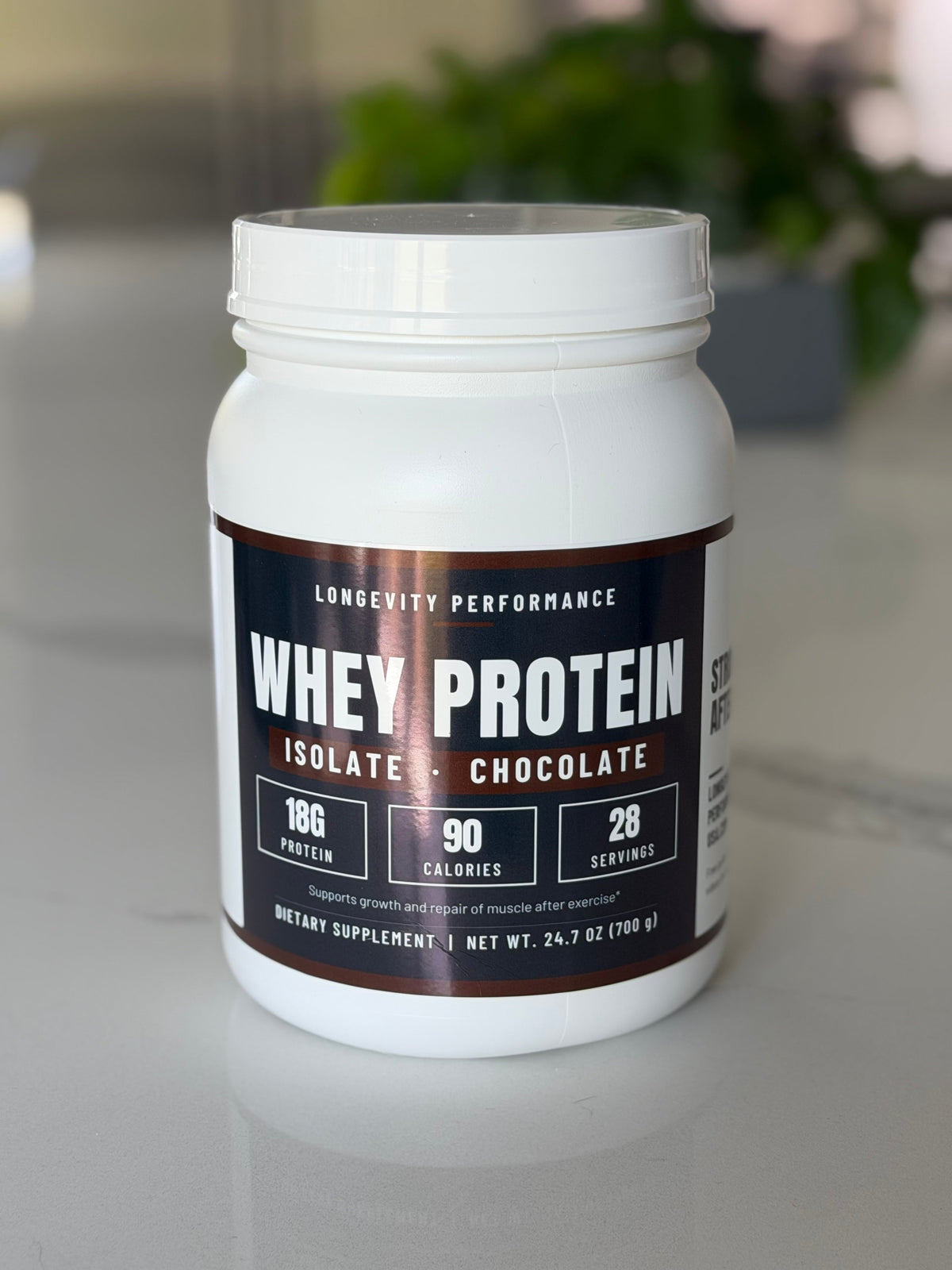 Longevity Performance Whey Protein Isolate Chocolate tub on a kitchen counter